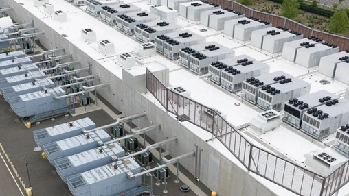 Aerial view of a data centre complex with rooftop HVAC arrays and electrical infrastructure along the building