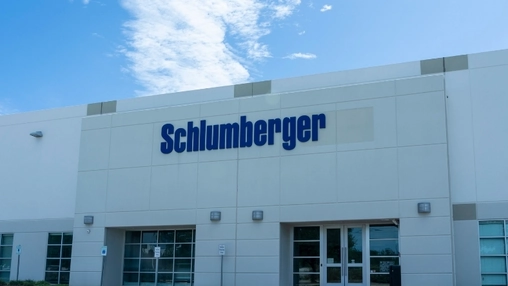 Large blue Schlumberger wordmark on a white commercial building exterior with glass entrance doors below
